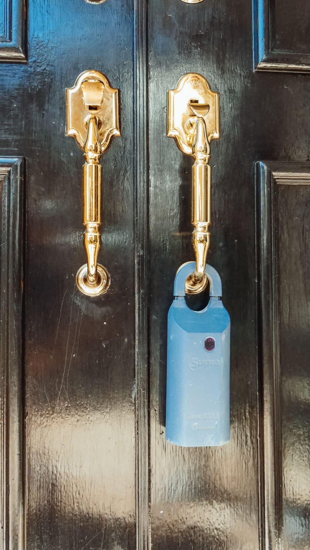 Black front door with brass handles and a lockbox